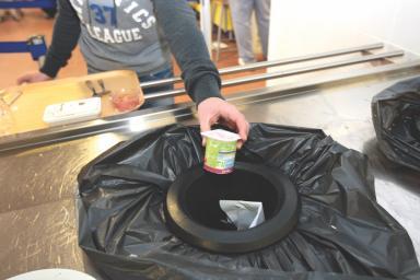 Un enfant met un pot de yaourt vide dans une poubelle de tri sélectif. Le visage de l'enfant n'est pas visible. - Agrandir l'image, fenêtre modale