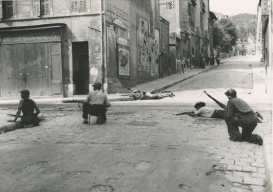 photo noir et blanc des soldats cachés au sol au coin d'une rue, fusil en mains, en position de tir - Agrandir l'image, fenêtre modale