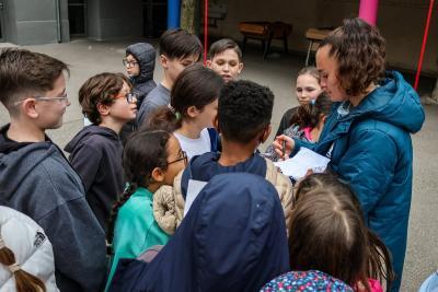 Une joueuse de l'Olympique de Marseille signe des autographes pour un groupe d'élèves enthousiastes rassemblés autour d'elle dans la cour du collège. - Agrandir l'image 9 sur 16, fenêtre modale