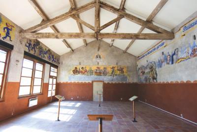 Salle mansardée, comportant des dessins au mur se rapprochant de scènes religieuses caricaturées telles que les 12 apôtres - Agrandir l'image 3 sur 6, fenêtre modale