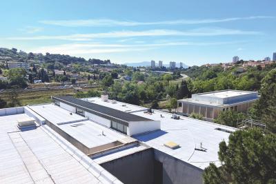 Les toits du collège Jean-Moulin (Marseille, 15e) en vue aérienne. Il fait beau et on aperçois Marseille dans le fond. - Agrandir l'image 1 sur 4, fenêtre modale