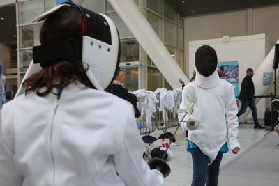 Deux adolescents se font face, tous les deux casqués avec un équipement d'escrime sur le haut du corps. en position de combat épée en main. - Agrandir l'image 6 sur 9, fenêtre modale