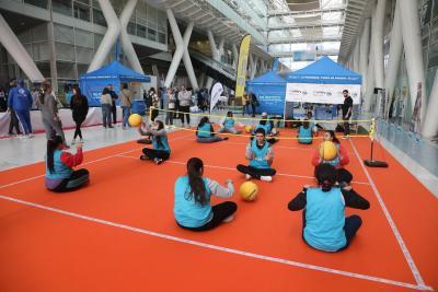 des enfants assis de par et d'autre un petit terrain de volleyball monté en intérieur avec un petit filet. ils sont assis deux par deux face à face et se renvoient des ballons - Agrandir l'image 3 sur 9, fenêtre modale