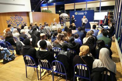 Vue d’ensemble d’une salle avec un public assis sur des chaises bleues, face à une scène où deux intervenants s’expriment devant un panneau « Département Bouches-du-Rhône ». - Agrandir l'image 1 sur 6, fenêtre modale