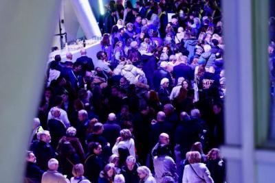 Grande foule rassemblée dans un hall moderne éclairé de lumières violettes et bleutées lors d’un événement - Agrandir l'image 11 sur 20, fenêtre modale