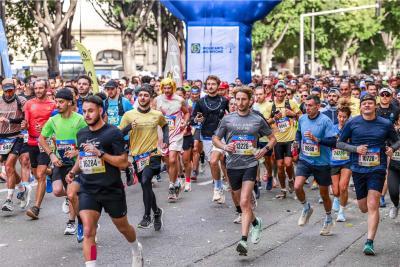 Groupe de coureurs participant au semi-marathon Marseille-Cassis, portant des dossards colorés, sous une arche bleue et entourés d’arbres en arrière-plan. - Agrandir l'image 4 sur 12, fenêtre modale