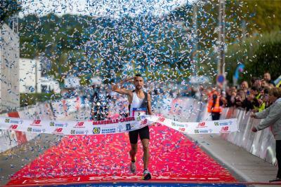 Coureur franchissant la ligne d’arrivée du semi-marathon Marseille-Cassis sous une pluie de confettis bleus, avec un tapis rouge au sol et des spectateurs derrière les barrières. - Agrandir l'image 11 sur 12, fenêtre modale