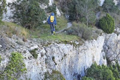 une personne de dos marchant sur un sentier le long d'une paroi rocheuse - Agrandir l'image 2 sur 5, fenêtre modale