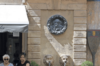 une fontaine contre le mur avec deux têtes de lion en pierre d'où s'écoule l'eau - Agrandir l'image 3 sur 8, fenêtre modale