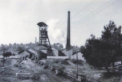 photo en noir et blanc d'une usine avec des petits bâtiment, une tour métallique et une longue cheminée - Agrandir l'image 6 sur 7, fenêtre modale