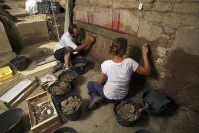 deux personnes travaillant minutieusement sur le nettoyage d'une fresque découverte contre un mur. - Agrandir l'image 11 sur 14, fenêtre modale