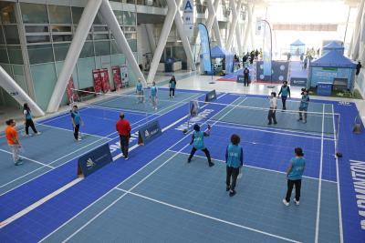 Participants jouant au badminton sur des terrains bleus à l’intérieur d’un hall. - Agrandir l'image 6 sur 15, fenêtre modale